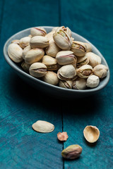 Pistachios on petrol-colored wood in bowl