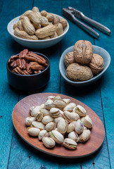 Peanuts pistachios walnuts and pecans on petrol wood