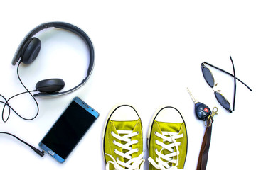 Sneaker shoes , mobile phone and other  accessories such as headphone , car key and eyeglass on white background , top view and copy space