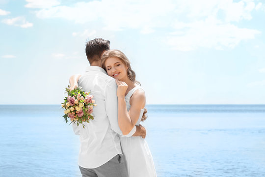 Happy newlywed couple hugging on seashore