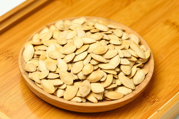 pumpkin seeds in wooden plate isolated on white background