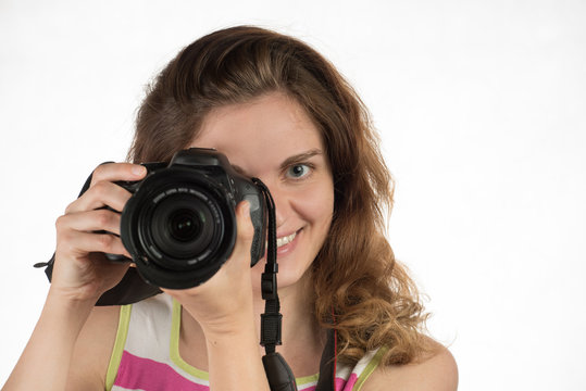 Young beautiful girl smiles and holds a camera on a white background