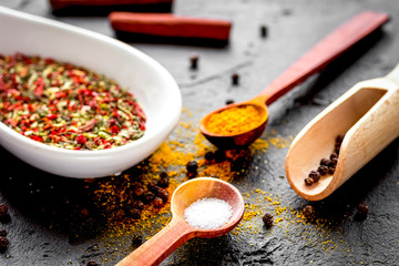 spices in wooden spoon on dark background