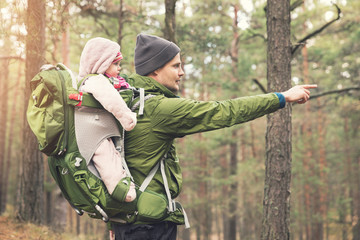 father with baby in child carrier on a hike in the woods