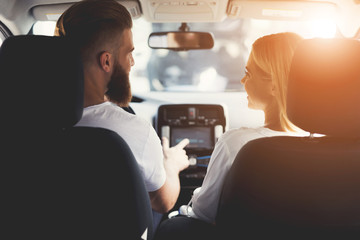 A young couple is sitting in the cabin of a comfortable modern electric car.