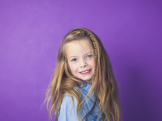 Fototapeta premium young 8 year old girl portrait in front of violet background in studio