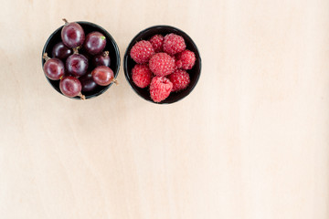 Two bowls with raspberry and gooseberry, top view, space for text.