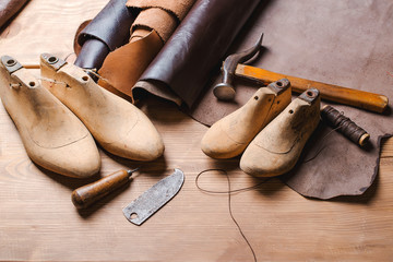 Leather in rolls, cobbler tools and shoe lasts in workshop. Leather craft tools. - Powered by Adobe