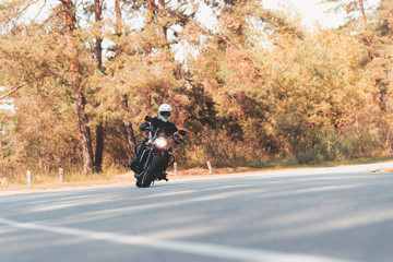 A young guy in a helmet is riding on a forest road on an electric motorcycle.
