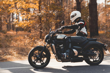 A young guy in a helmet is riding on a forest road on an electric motorcycle.