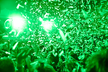 Confetti fired in the air during a in a disco. Hundreds of hands to the sky. Green tone/background