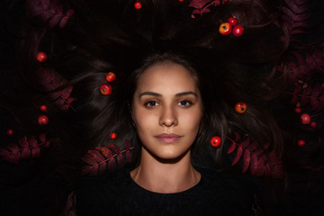 Autumn woman portrait lying on the ground with red apples