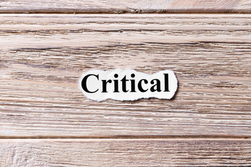 CRITICAL of the word on paper. concept. Words of CRITICAL on a wooden background