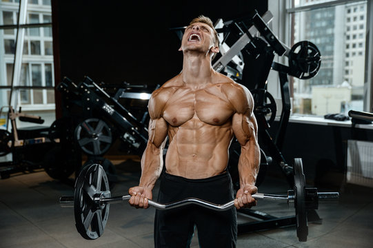 Handsome model young man training arms in gym