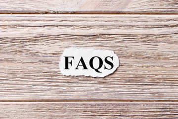 FAQS of the word on paper. frequently asked questions concept. Words of FAQS on a wooden background