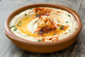 Chickpea hummus in bowl on wooden table.