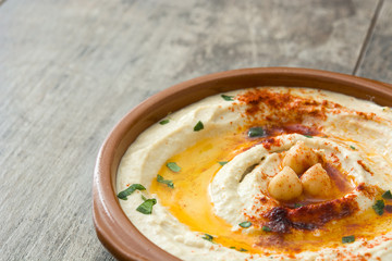 Chickpea hummus in bowl on wooden table.