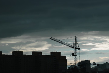 Fototapeta premium Industrial construction cranes and building silhouettes over sun at sunrise.