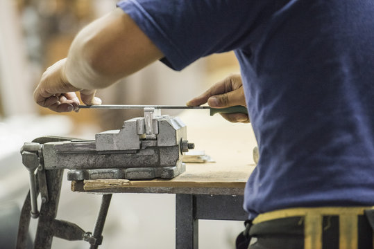 Man using file and vise in workshop, cropped
