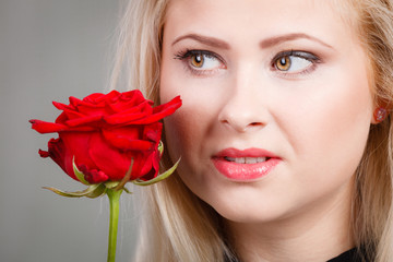 woman holding red rose near face looking melancholic