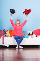 Woman sitting on messy couch throwing clothes