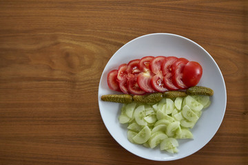 Sliced Tomatoes And Cucumbers With Pickles On a White Plate With Wooden Background