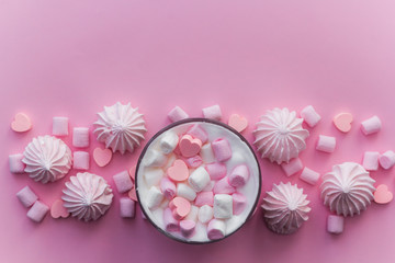 Fototapeta na wymiar Top view hot beverage with whipped cream,marshmallows and heart shaped chocolate candies on pink pastel background