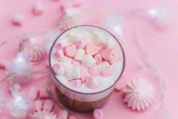 Obraz na płótnie Canvas Top view hot beverage with whipped cream,marshmallows and heart shaped chocolate candies on pink pastel background