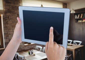 Hand holding tablet with cafe background