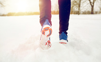 close up of feet running along snowy winter road