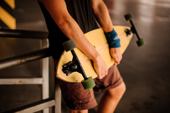 Young man holding a yellow longboard in hands