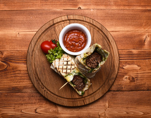 Minced meat wrapped with lavash bread on wooden background