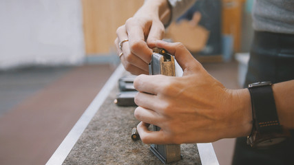 Female's hands in shooting gallery loads the gun with bullets