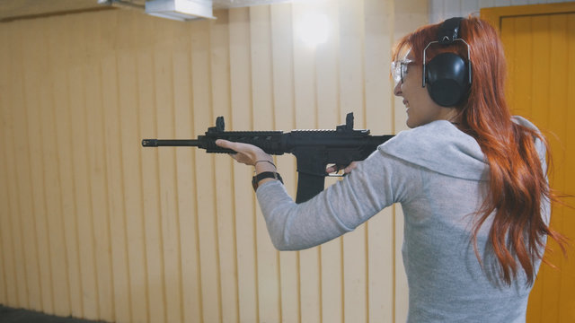 Woman shooting with a Mashin gun in shooting gallery
