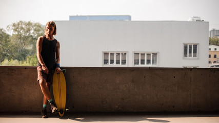 Portrait of man standing with a longboard