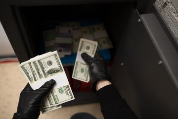 thief stealing money from safe at crime scene