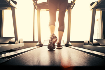 Lower body at legs part of Fitness girl running on running machine or treadmill in fitness gym with...
