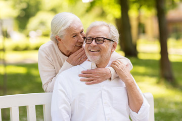 happy senior couple sitting on bench at park