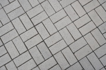 Light sidewalk tiles.  View from above.  Rectangular shapes.  Diagonal lines.  Grainy surface.  Footpath.  The city sidewalk.