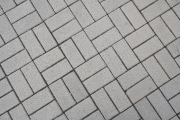 Light sidewalk tiles.  View from above.  Rectangular shapes.  Diagonal lines.  Grainy surface.  Footpath.  The city sidewalk.