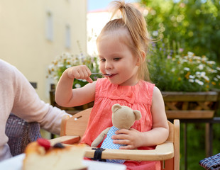 little girl with spoon eating outdoors
