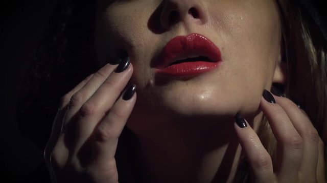Witch with black nails stroking her face, slow motion