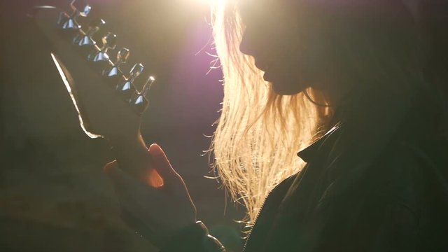 woman Guitarist silhouette in a backlights in the smoke playing solo and sing