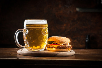 A glass of fresh cold light beer with gourmet hamburgers and wheat in a bar and a dark pub