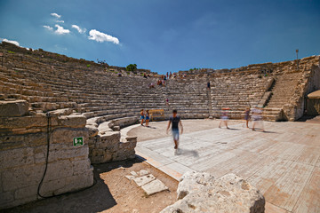 Some tourists visit the ruins of the ancient Greek theater of Segesta in Sicily, Italy.