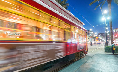 NEW ORLEANS - FEBRUARY 11, 2016: New Orleans streetcar at night, blurred view. The city attracts 15 million tourists every year - obrazy, fototapety, plakaty