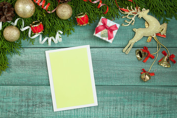 Christmas background or Xmas card. Holiday decorations and notebook with wish list on green rustic table, flat lay style. Planning concept.