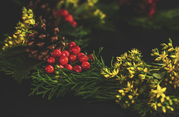 Christmas decorative wreath  with ornament  on black background. Made from thuja, flower, pine...