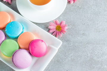 Photo of cake macarons, gift box, tea, coffee, cappuccino and flowers. Sweet romantic food macaroon concept. Morning breakfast and presents.