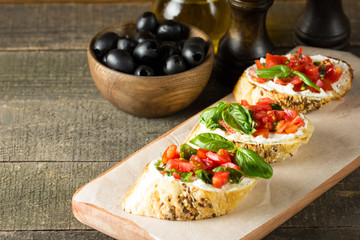 Tomato and cheese fresh made bruschetta. Italian tapas, antipasti with vegetables, herbs and oil on grilled ciabatta and baguette bread.